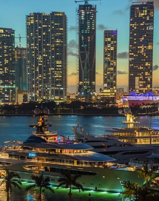 Miami waterfront restaurant and luxury event venue view with yachts and skyline at sunset.
